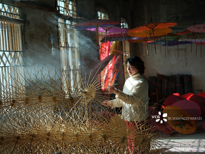 一位亚洲女性正在制作油纸伞图片素材