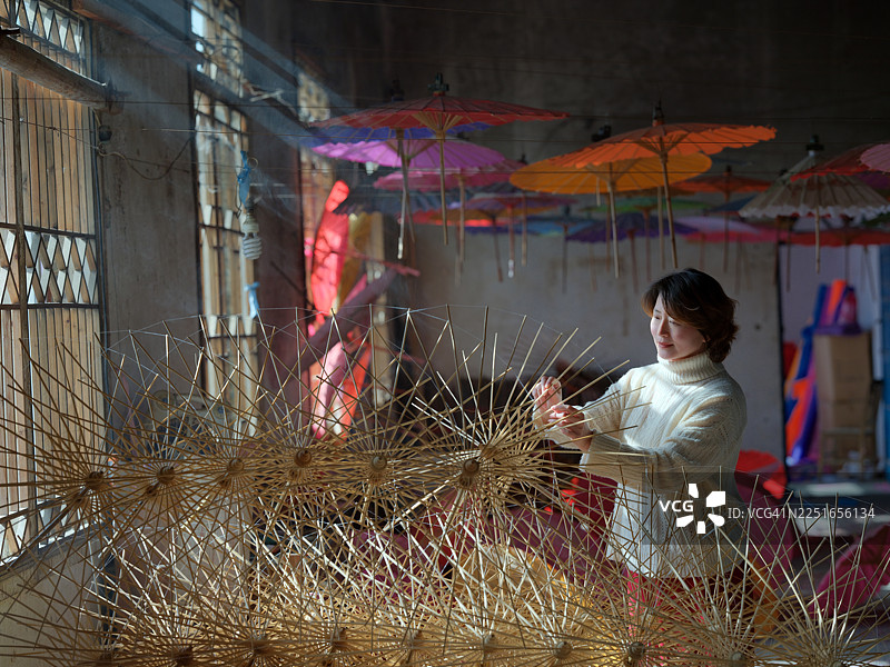 一位亚洲女性正在制作油纸伞图片素材