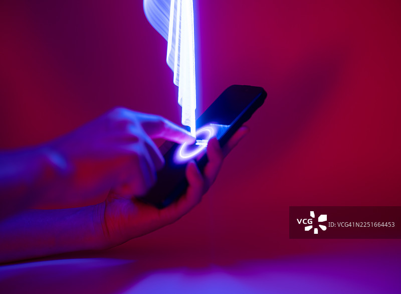 手持智能手机的特写。长曝光光绘。网络安全与人工智能的概念。图片素材