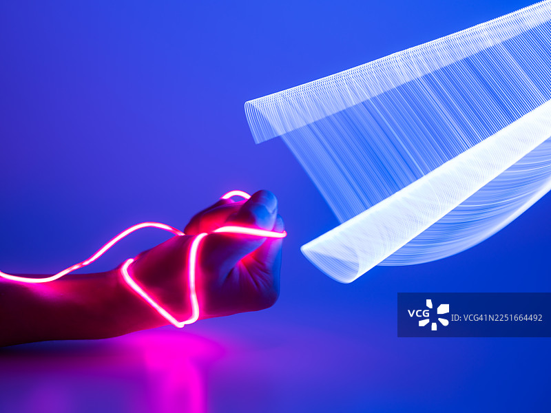 一只手拿着LED灯带的特写。长曝光光绘。图片素材