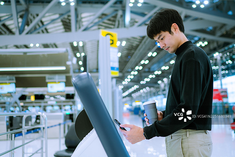 亚洲男子提前来到机场，并在自助值机柜台办理了值机手续图片素材