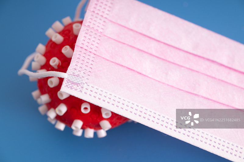 粉色防护口罩覆盖在病毒上，象征着安全、健康保障和预防图片素材