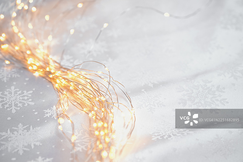 白色织物搭配雪花背景的平面布置图。金色串灯图片素材