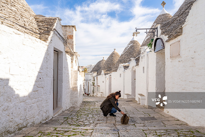 一位女士在意大利历史悠久的阿尔贝罗贝洛村庄里抚摸一只猫图片素材