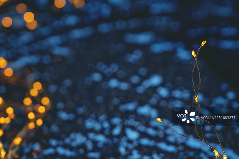 抽象的节日蓝色背景，带有金色串灯和闪亮的散景，可供模仿图片素材