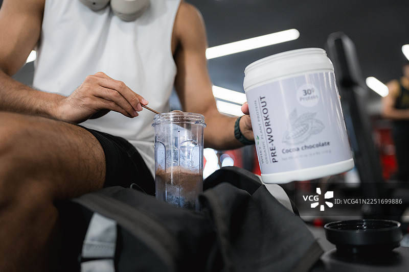 健壮的男士在锻炼前自信地坐在长凳上，饮用训练前乳清蛋白奶昔图片素材