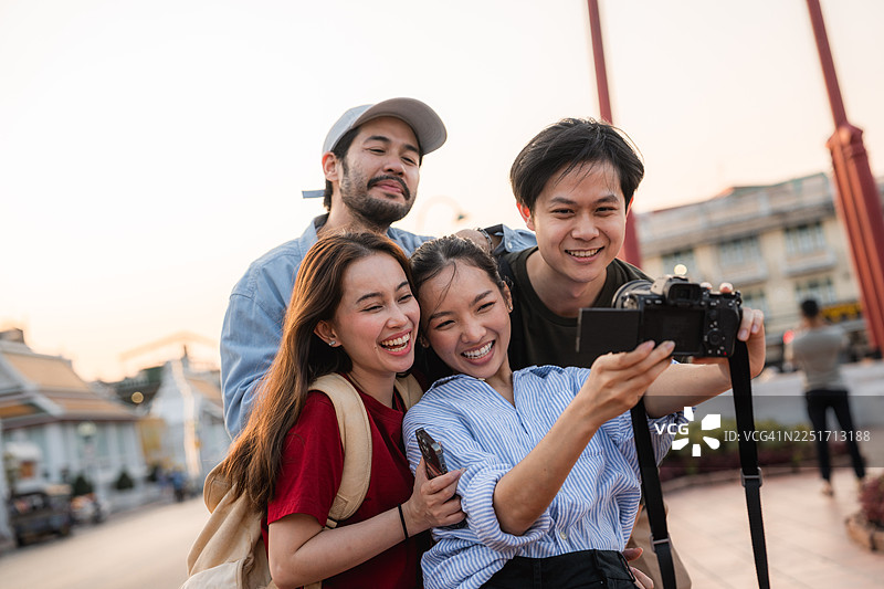一群朋友在探索曼谷城市时，用数码相机互相拍照并拍摄视频图片素材