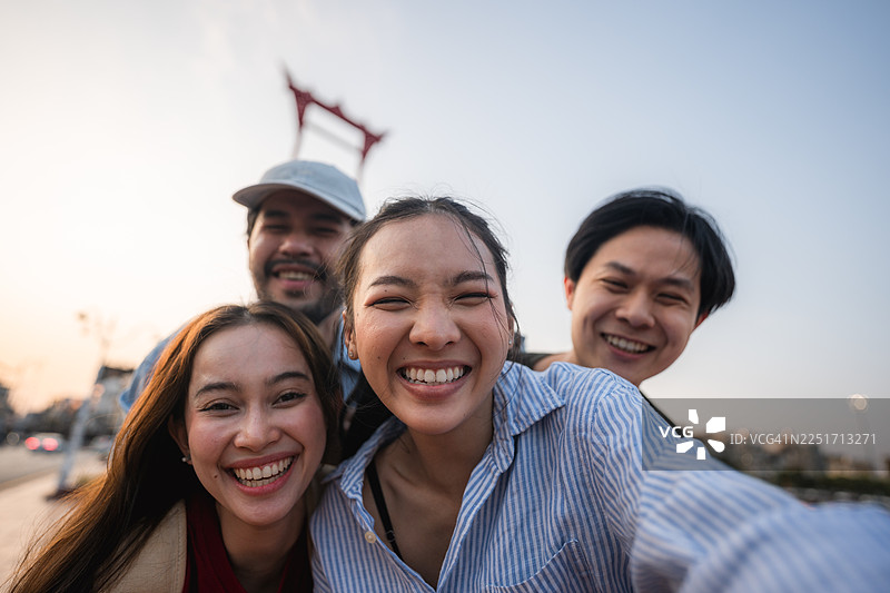 一群朋友在探索曼谷市时，用数码相机拍照并拍摄自己。图片素材