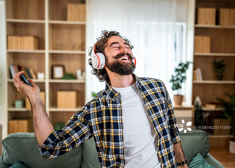 男子在家戴着耳机跳舞，享受音乐图片素材