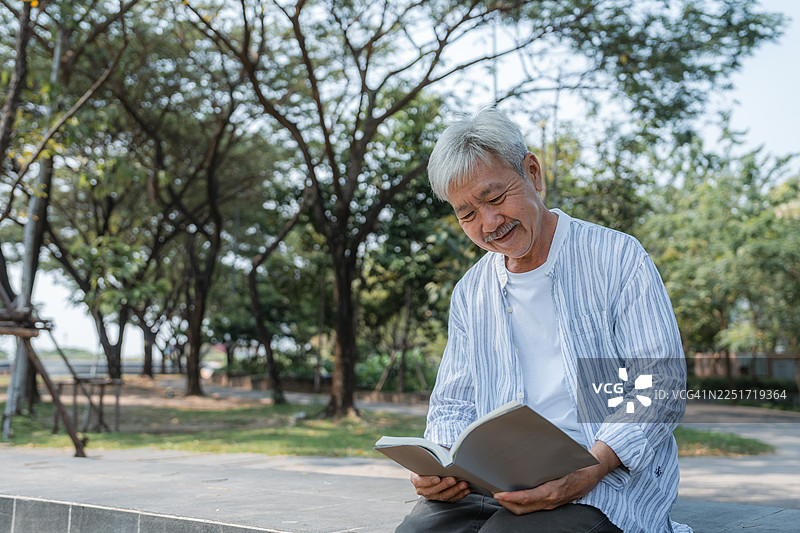 一位年长男性在公园里安详地阅读书籍图片素材