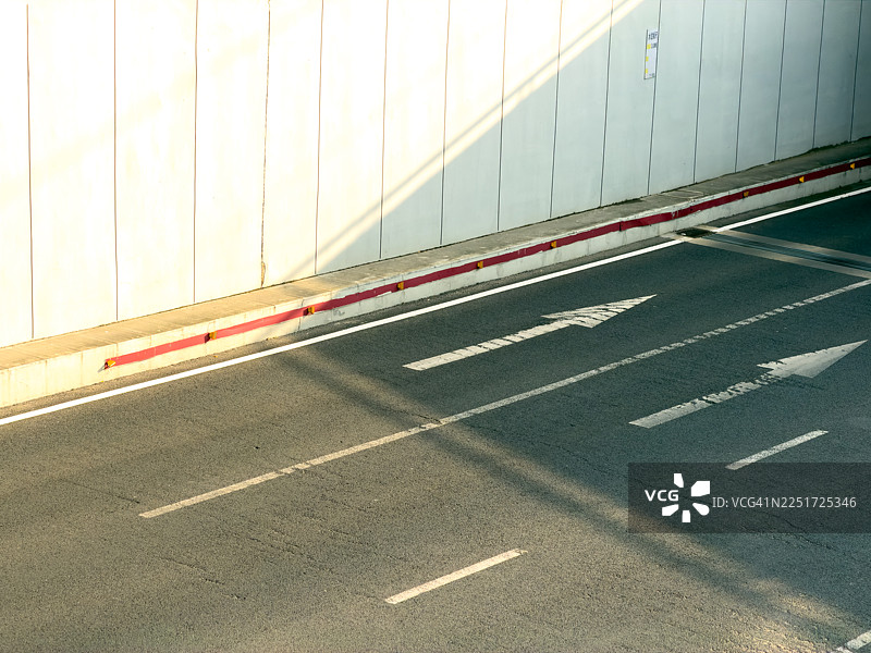 白色墙壁和带有箭头标记的沥青路图片素材