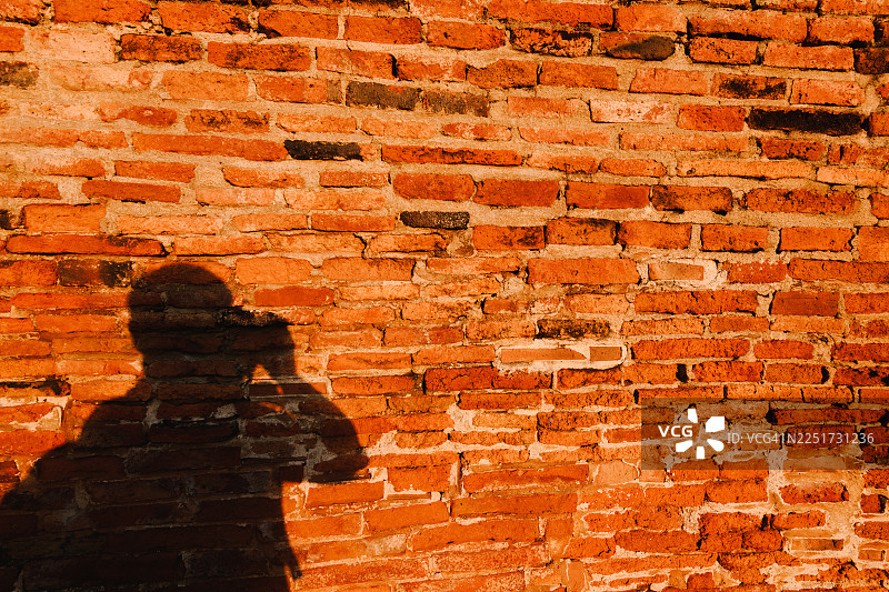 橙色砖墙上的男人剪影图片素材