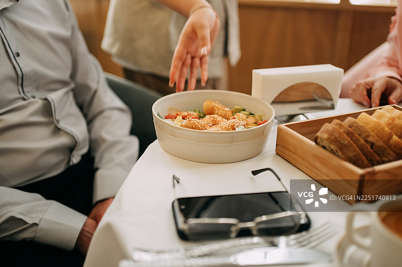 人们在餐厅用餐，享用沙拉和面包图片素材