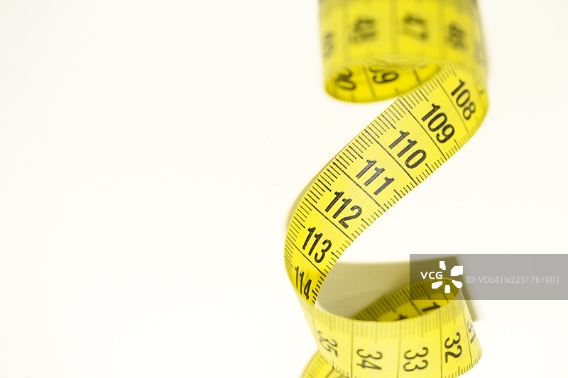 白色背景上的黄色卷尺，象征着精准，适用于健康、时尚、DIY和翻新项目的设计图片素材
