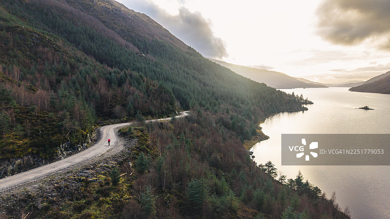 苏格兰高地，成熟男子沿着湖泊在砂石小径上骑行的航拍/无人机视角图片素材