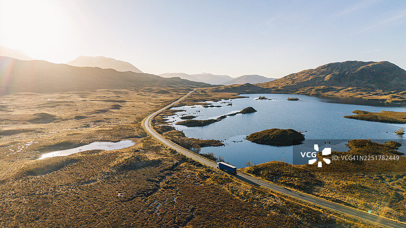 日出时分，苏格兰高地格伦科A82公路上的一辆卡车的鸟瞰/无人机视角，这是一个明亮的冬日图片素材