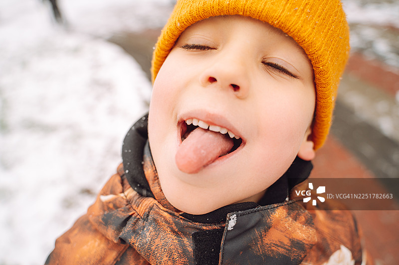 冬日里，小男孩伸出舌头品尝雪花。图片素材
