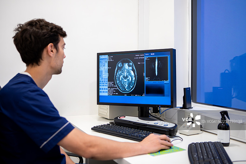 男放射技师在显示器上查看不同的核磁共振成像，并进行分析图片素材