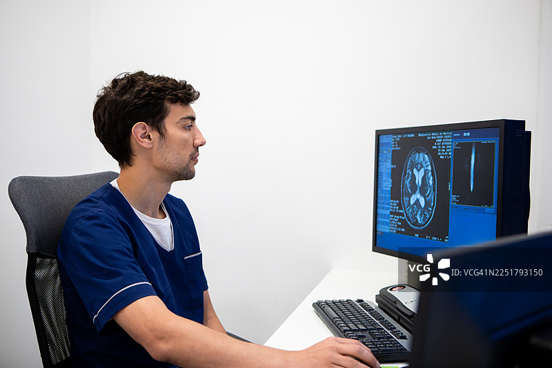 男性放射技师在显示器上查看不同的核磁共振成像并进行分析图片素材