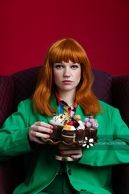 身着绿色套装的时尚女子享用精致甜点图片素材