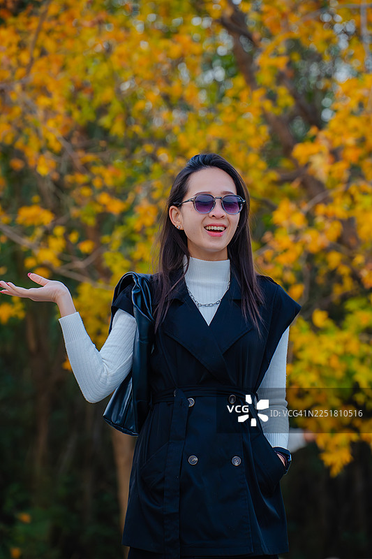 时尚女子戴着太阳镜在秋季公园摆姿势图片素材