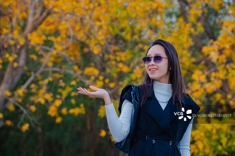 时尚女子戴墨镜在秋季公园摆姿势图片素材