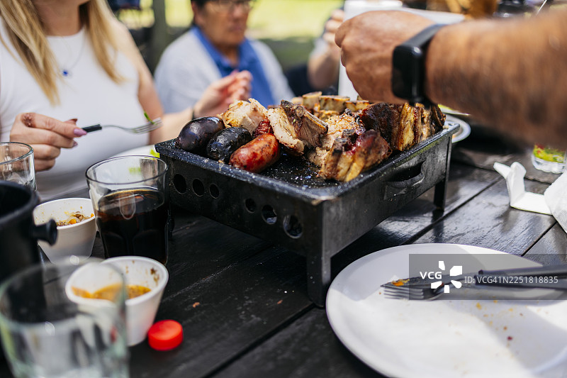 家人和朋友们在户外共享传统的烧烤大餐图片素材