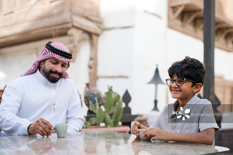 一位快乐的中东父亲在历史街区的户外咖啡馆与儿子愉快地交谈图片素材