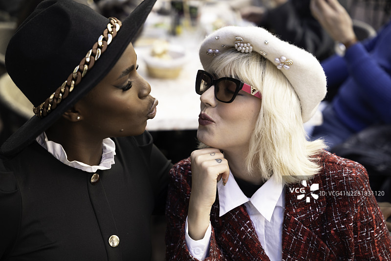 法国里维埃拉一家酒吧露台上，一位时髦的年轻女子正向她的朋友飞吻。图片素材