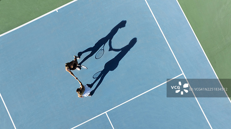 比赛结束后，两位年轻的女子网球运动员在网前握手图片素材