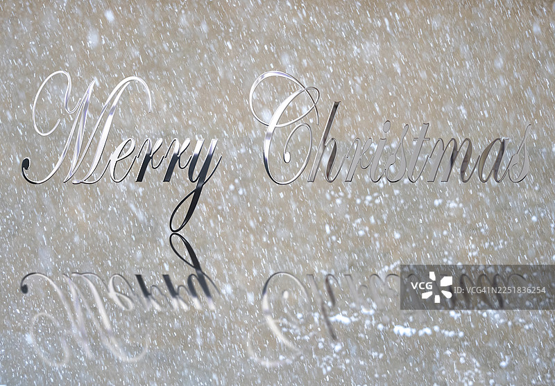 闪亮的银色圣诞快乐字母，伴随着窗外飘落的雪花。图片素材