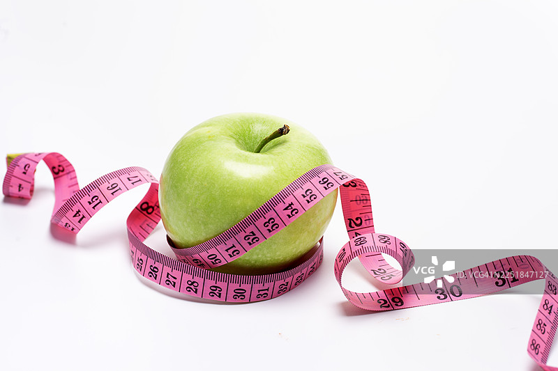 绿苹果与粉红色卷尺，背景为白色。图片素材