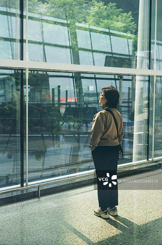 亚洲中年女性站在机场出发区图片素材