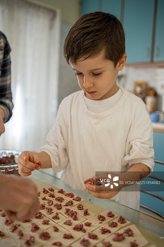 祖母与年幼的孩子在家庭厨房里一起准备自制饺子图片素材