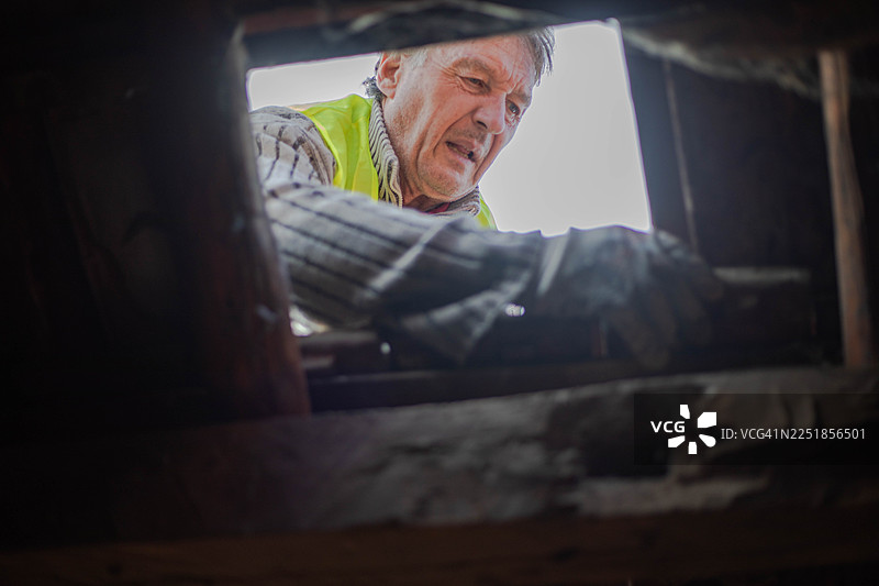 一位工匠——建筑工人正在修复建筑物的旧瓷砖屋顶图片素材