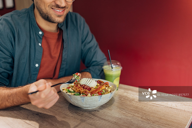 在快餐店，一位看不清脸的男士正在享用富含蛋白质的沙拉和超级食物饮品图片素材