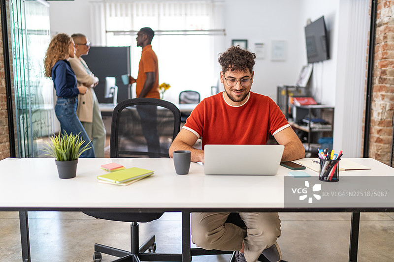 年轻男子在现代共享办公空间使用笔记本电脑图片素材