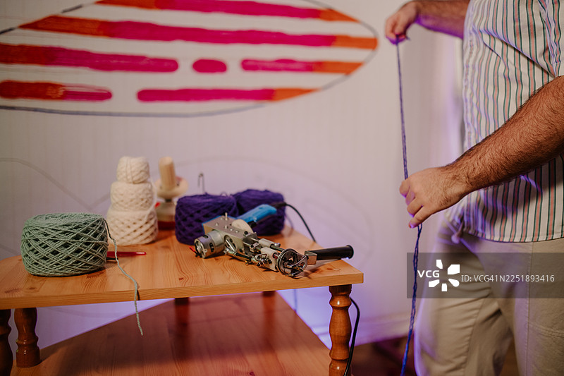 男人用纱线和工具制作簇绒地毯图片素材