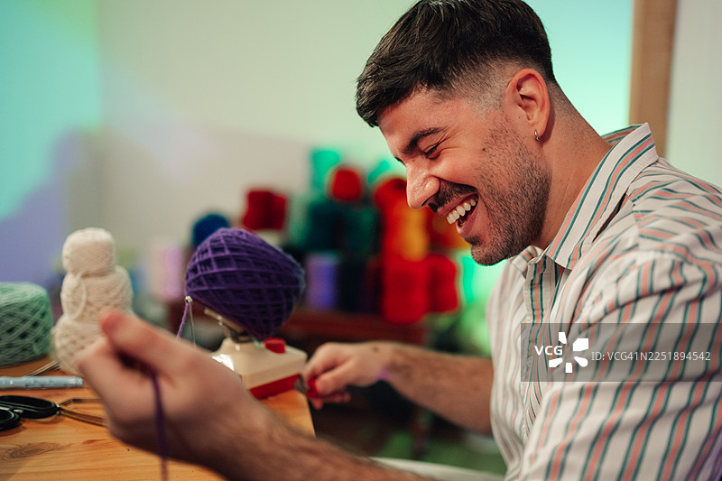 男人笑着使用绕线器进行编织爱好图片素材