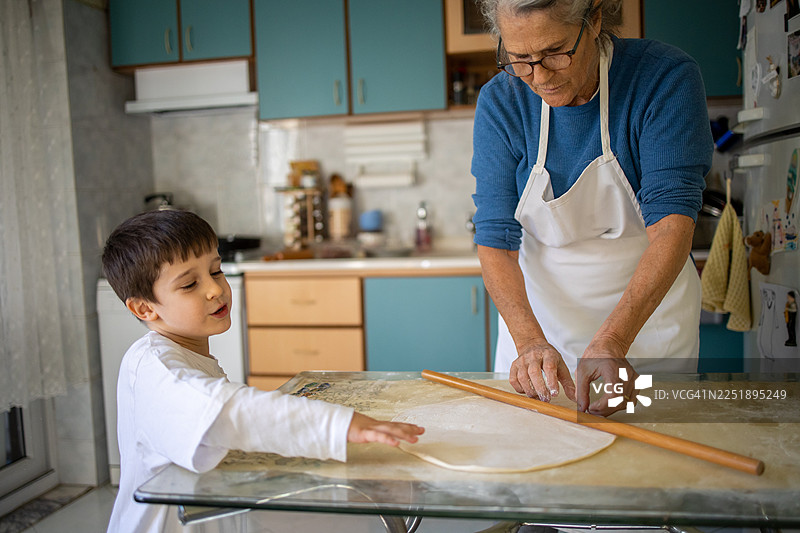 祖母和孙辈在家里的厨房一起烘焙，擀面团图片素材