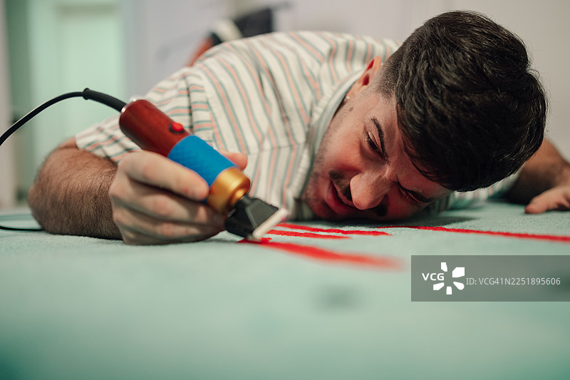 男人修剪簇绒地毯，创造出独特的图案图片素材