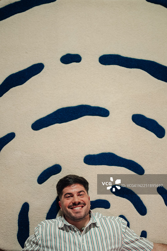 快乐的年轻成年男子在抽象地毯上放松图片素材