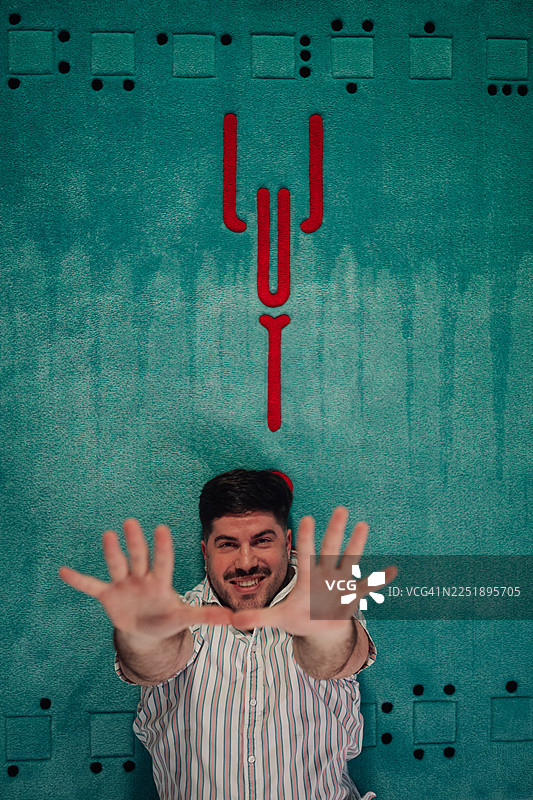 快乐的男人躺在地毯上，双手向上伸展图片素材