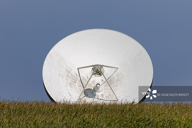 广阔的草地后方是一个大型抛物面天线图片素材