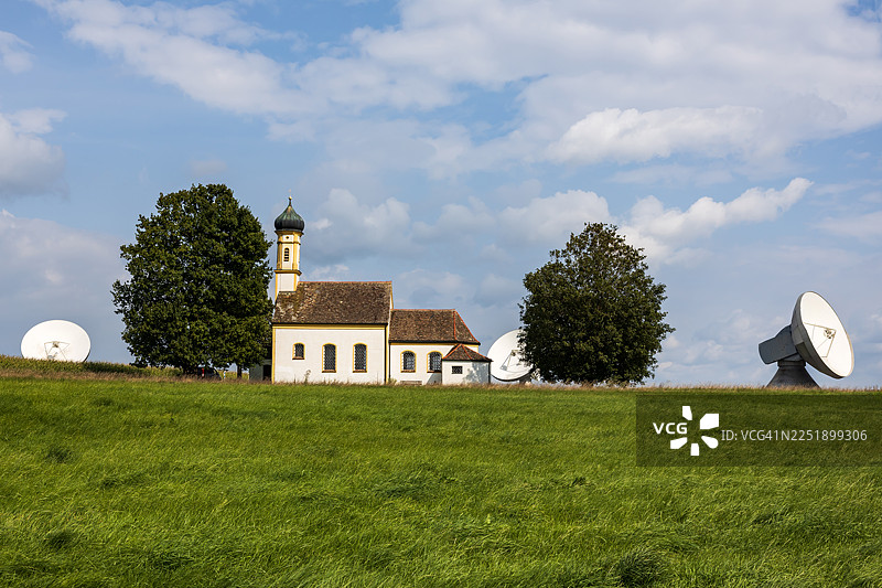 德国巴伐利亚州劳斯汀地球站的抛物面天线与历史悠久的教堂图片素材