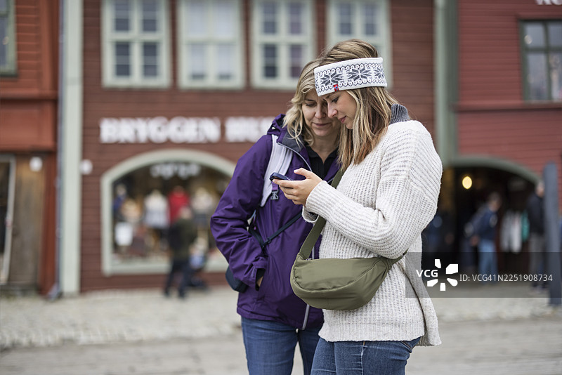 一位母亲和她成年的女儿在卑尔根布吕根码头前查看智能手机图片素材