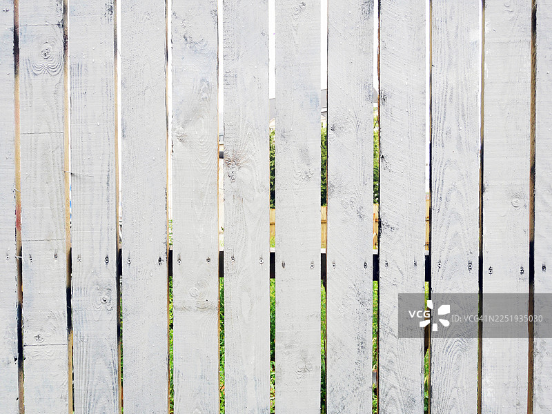 特写镜头，白色的木栅栏，栅栏之间可以看到花园的草坪。阳光，自然色彩。比利时布鲁塞尔。图片素材