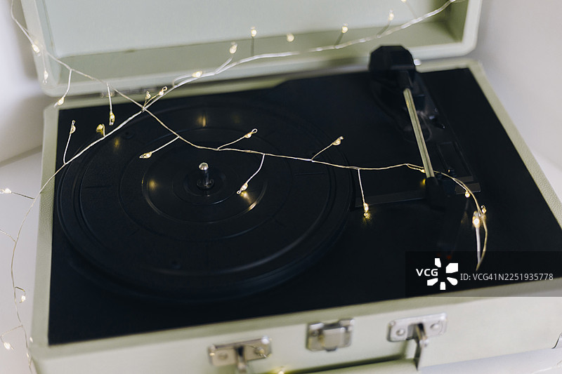 一款复古手提箱式黑胶唱片机，配有黑色唱片和串灯。图片素材