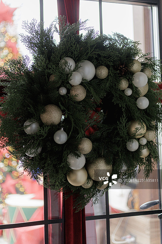 一个圣诞花环，装饰着白色和金色的圣诞球，挂在一扇门上。图片素材
