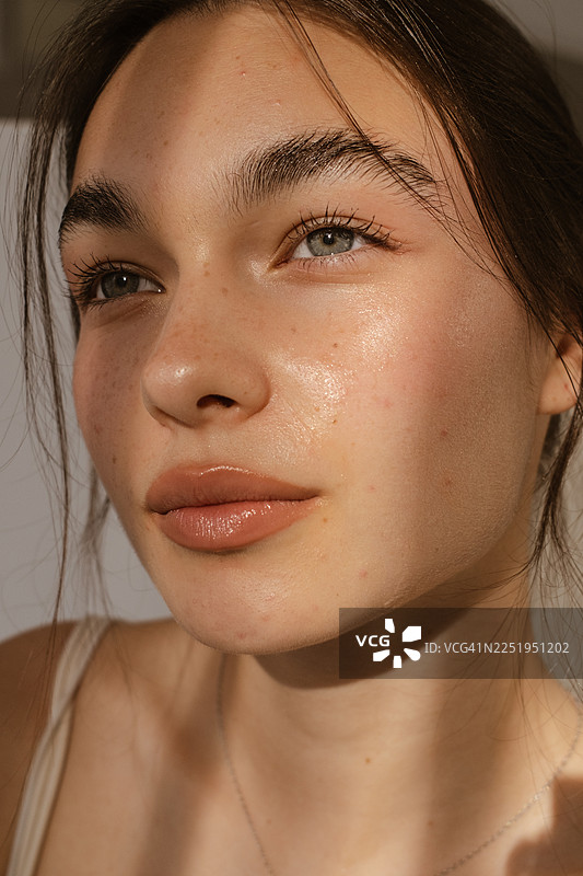 阳光下，一名女子面部特写，肌肤洁净水润图片素材